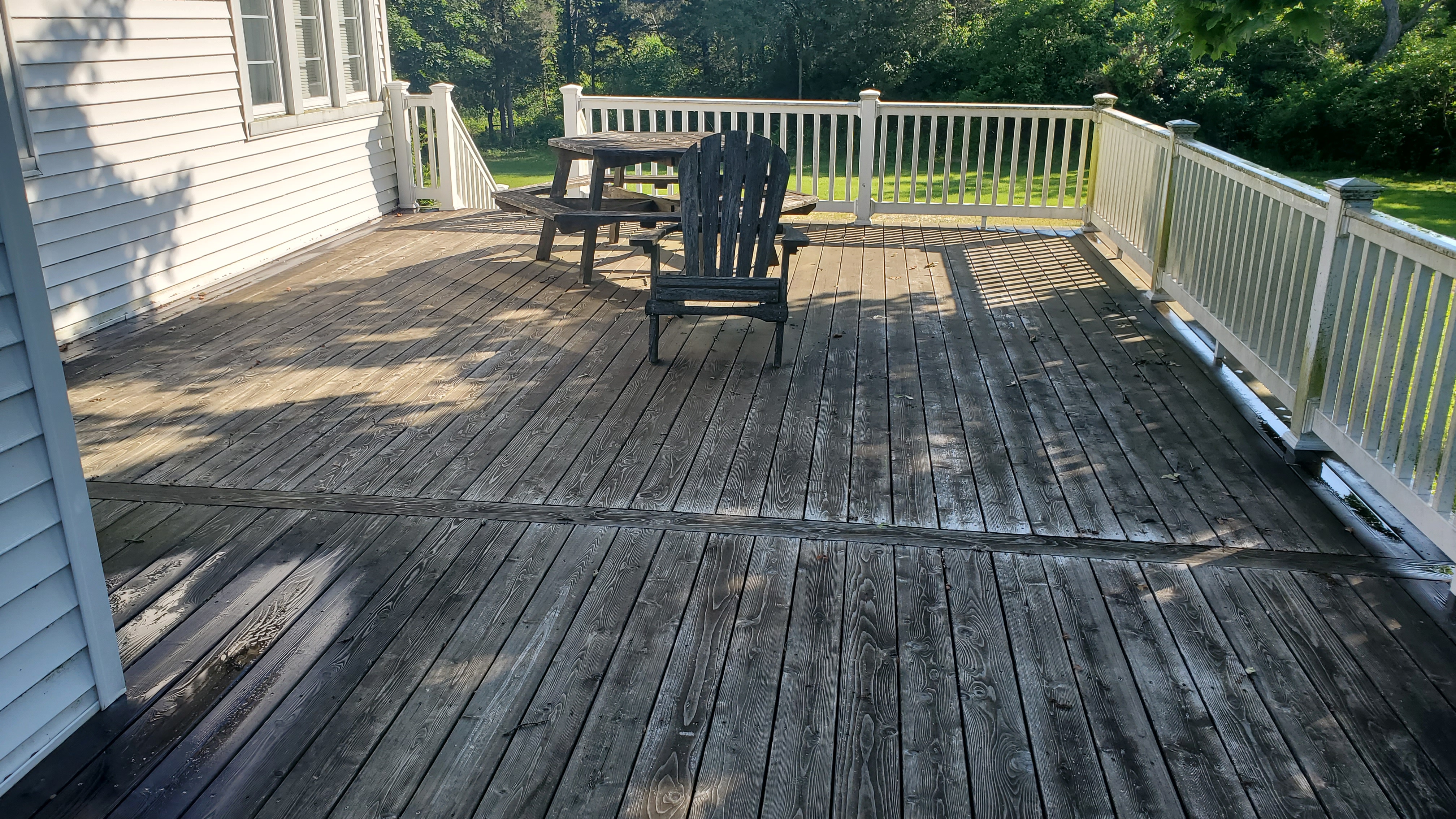 Heavily weathered grey wood deck covered in black mold and years of discoloration before cleaning