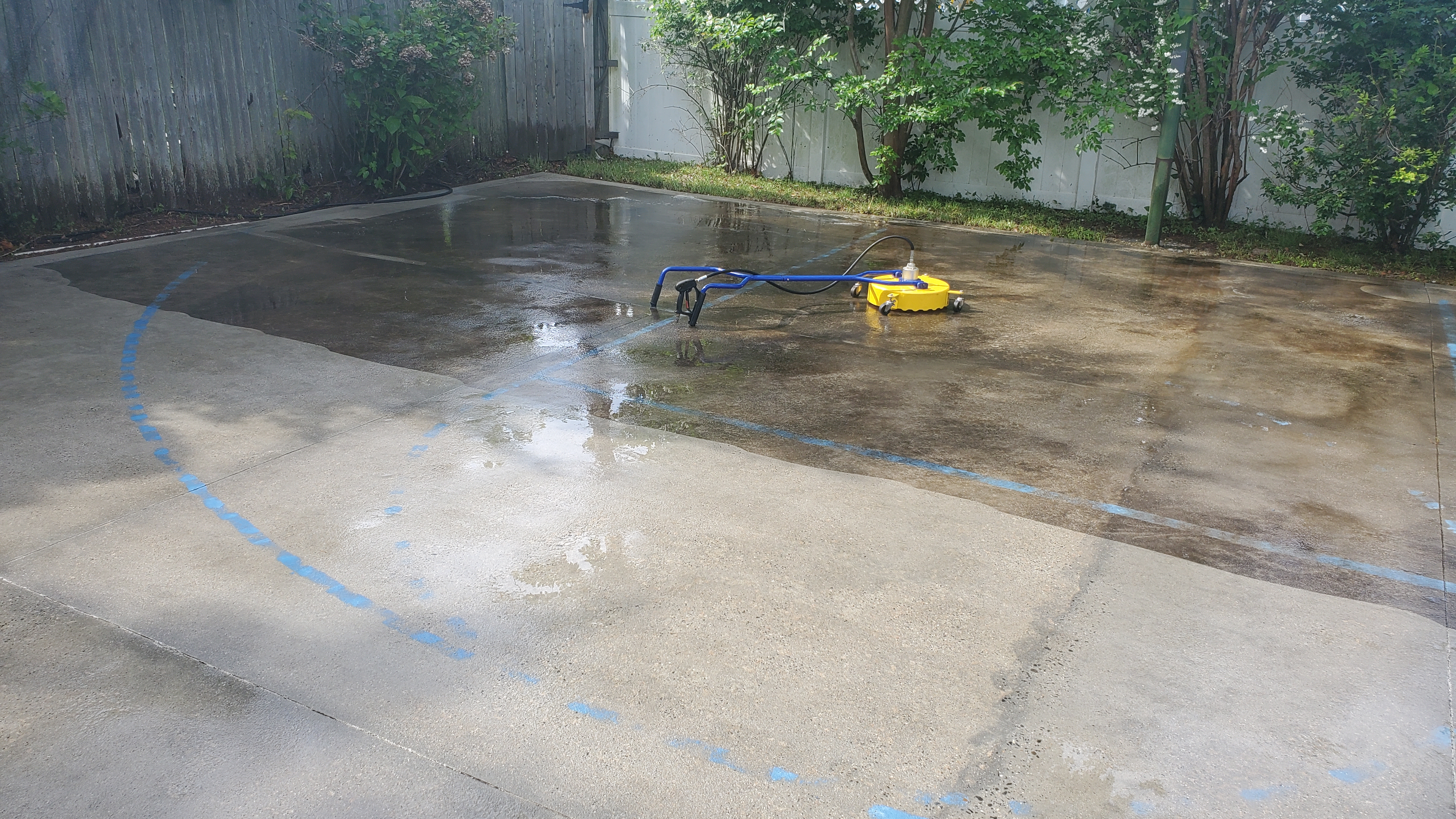 Professional surface cleaner being used on concrete patio showing dramatic clean vs dirty contrast