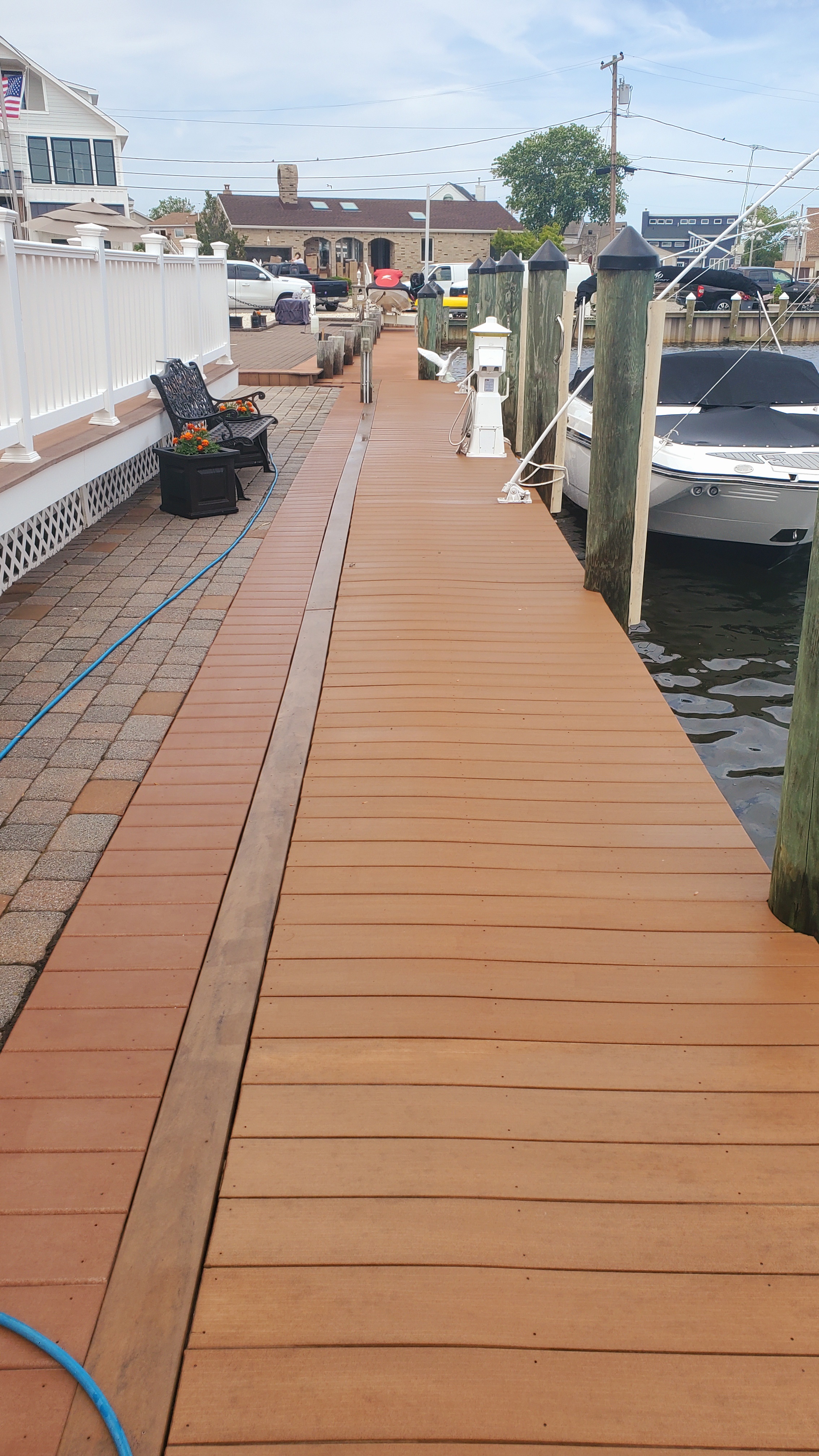Freshly cleaned waterfront composite dock extending over water with boat docked alongside