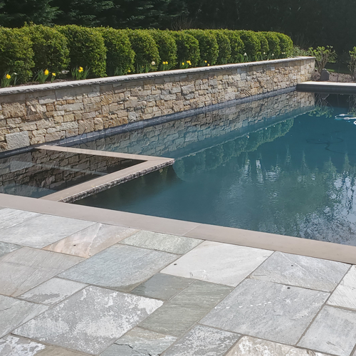 Professionally cleaned slate stone pool deck and elegant stone wall surround with crystal clear pool water