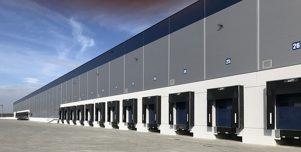 Large modern warehouse facility with loading docks and clean exterior — commercial power washing service